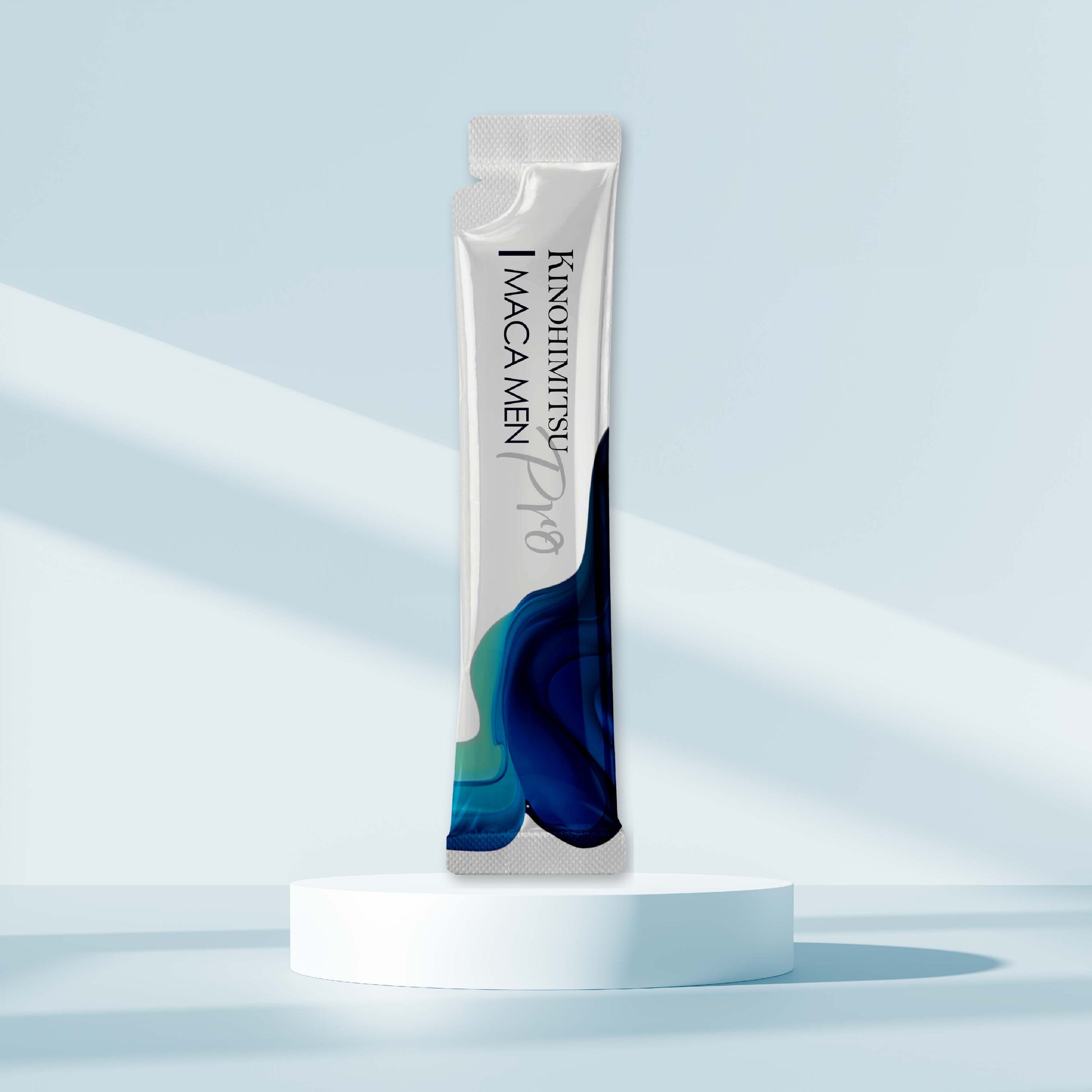 Kinohimitsu Maca Men Pro sachet on a white pedestal with a light blue background, featuring a modern packaging design with blue and green accents. Kinohimitsu Maca Men Pro sachet on a pedestal against a light blue background. Maca Men Pro product by Kinohimitsu Malaysia displayed on a minimalist podium with a light blue background. The packaging is sleek with a modern design, featuring abstract blue and green patterns.