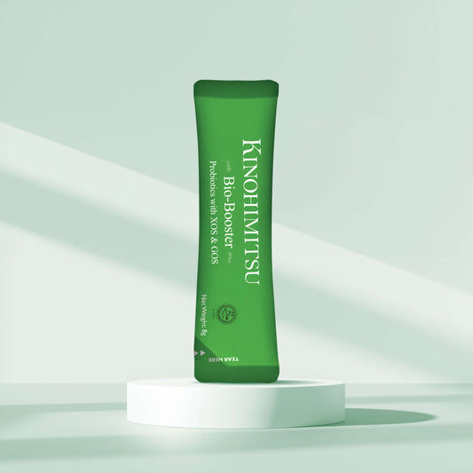 Kinohimitsu Bio-Booster sachet standing on a white platform against a light green background, featuring probiotic supplement promotion.